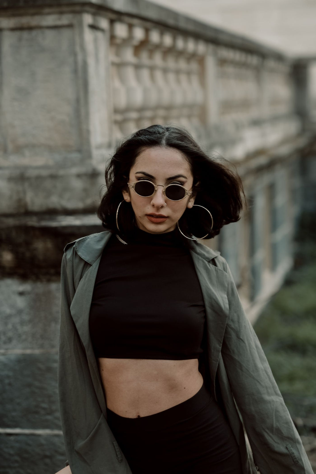 Woman wearing sunglasses and large hoop earrings in a city street outfit