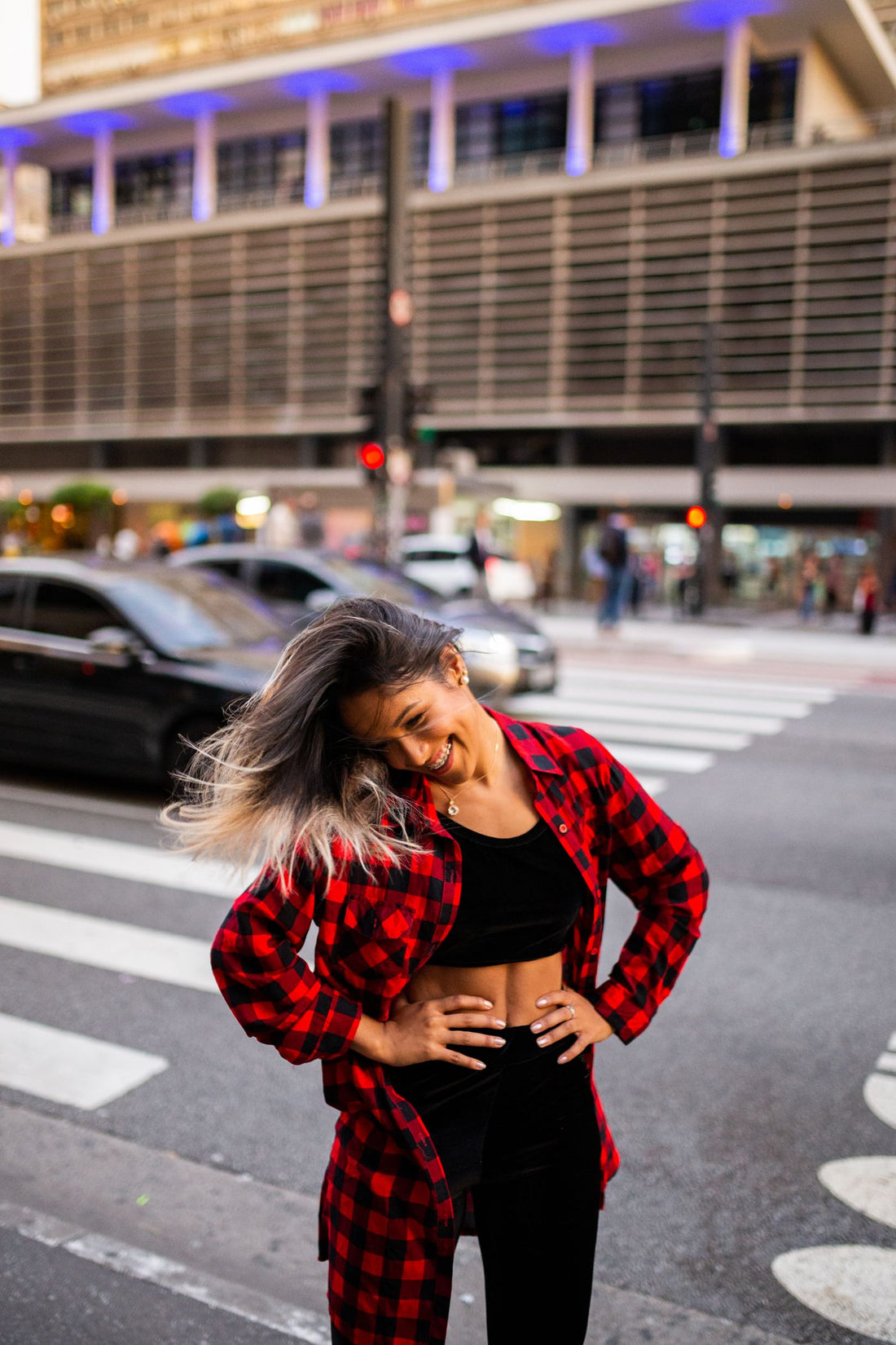 Street-style model wearing a red plaid shirt at a city crosswalk
