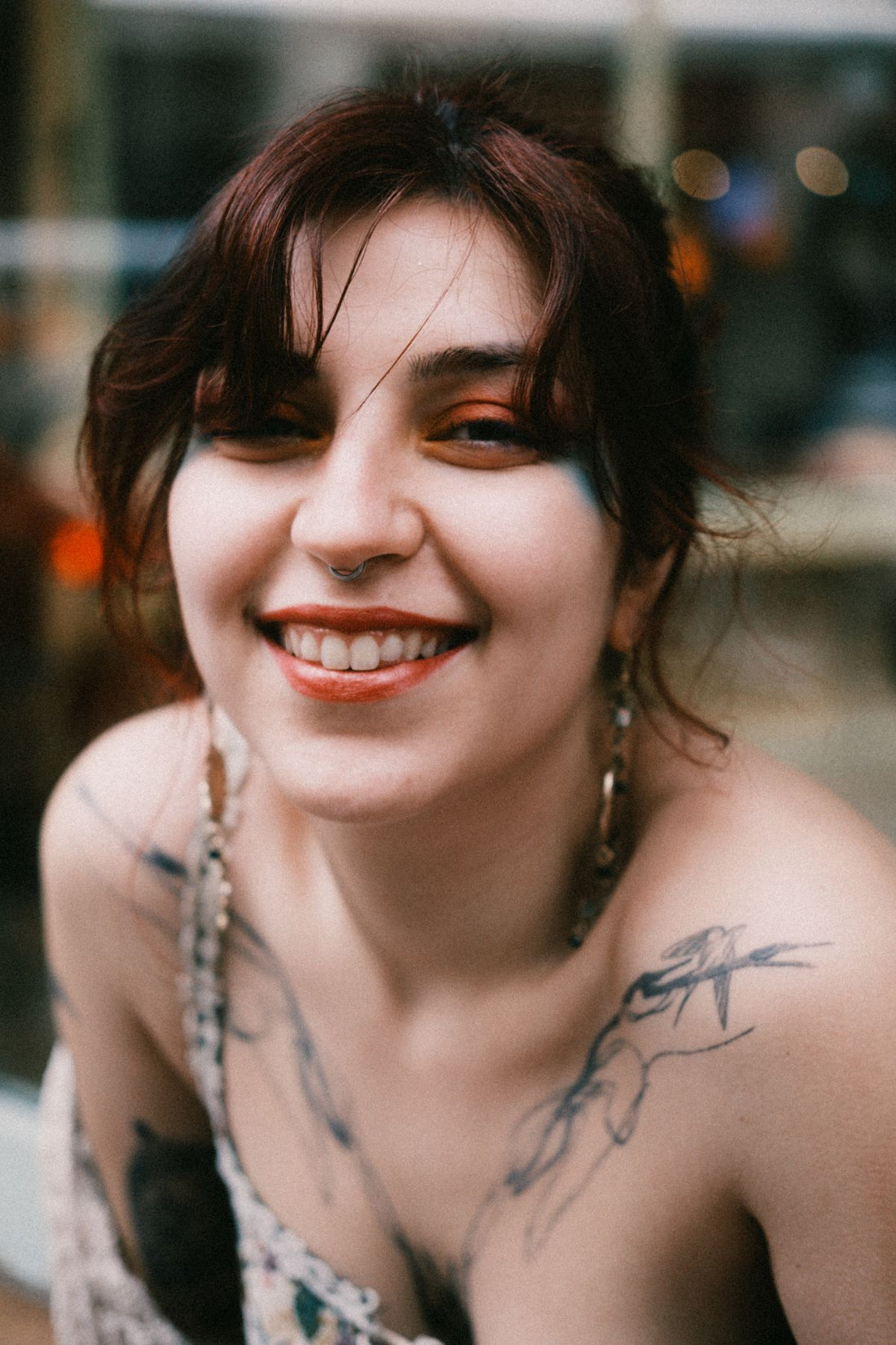 Lifestyle portrait of a smiling model with a septum ring in a casual cafe setting