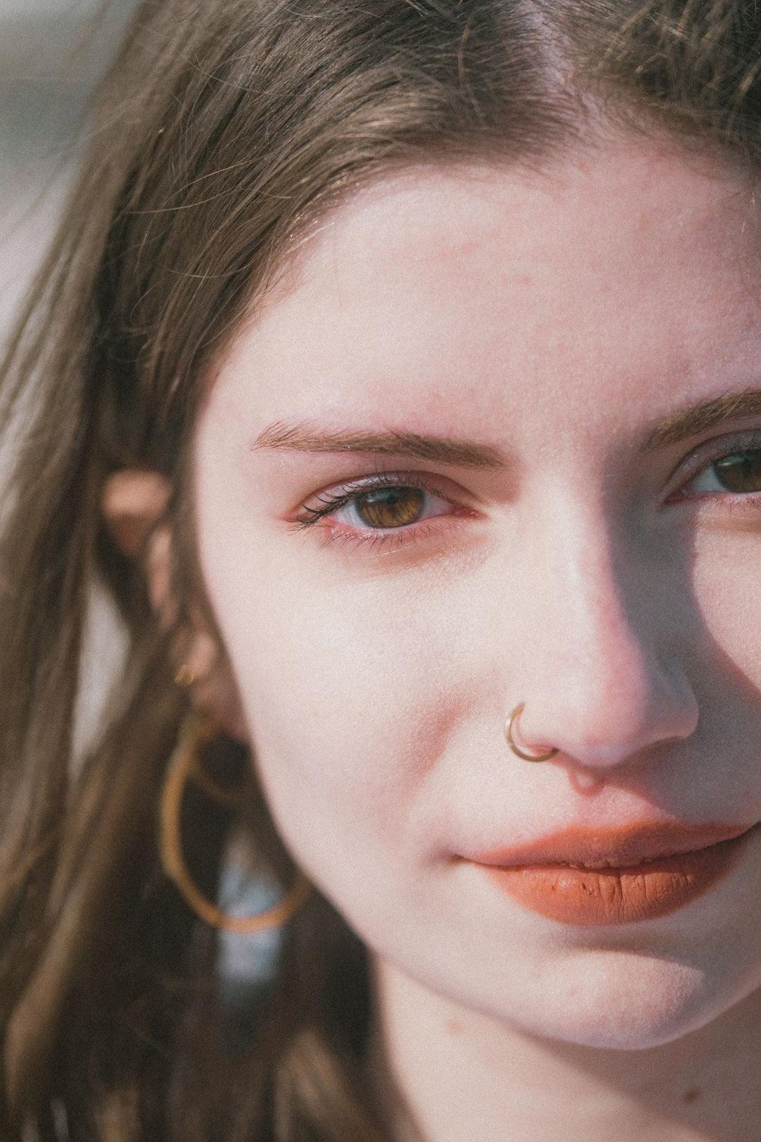 Minimal close-up portrait of a woman with nose jewelry and soft morning light