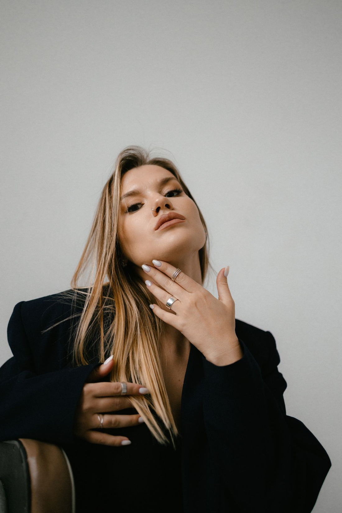 Portrait of a blonde model with a delicate nose ring and stacked jewelry