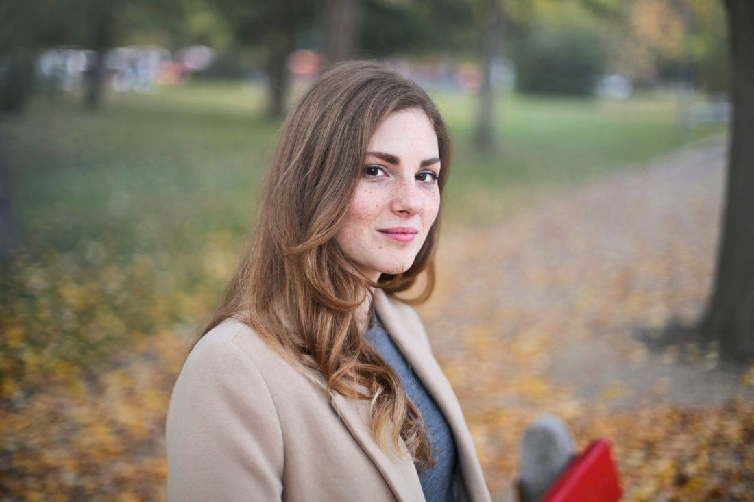 Woman in a camel coat outdoors for a soft city-walk jewelry styling guide