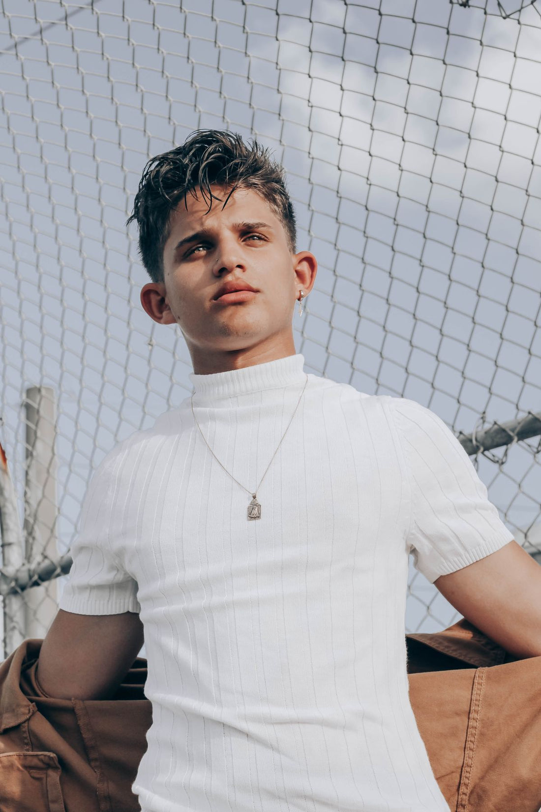 Portrait of a male model with earrings and layered streetwear styling