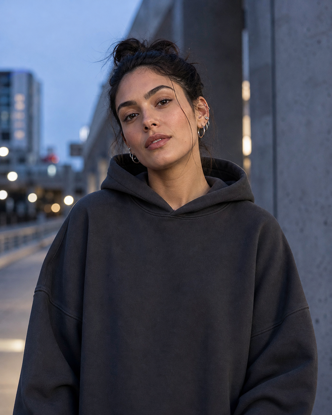 Streetwear model in a charcoal hoodie wearing a layered silver ear stack