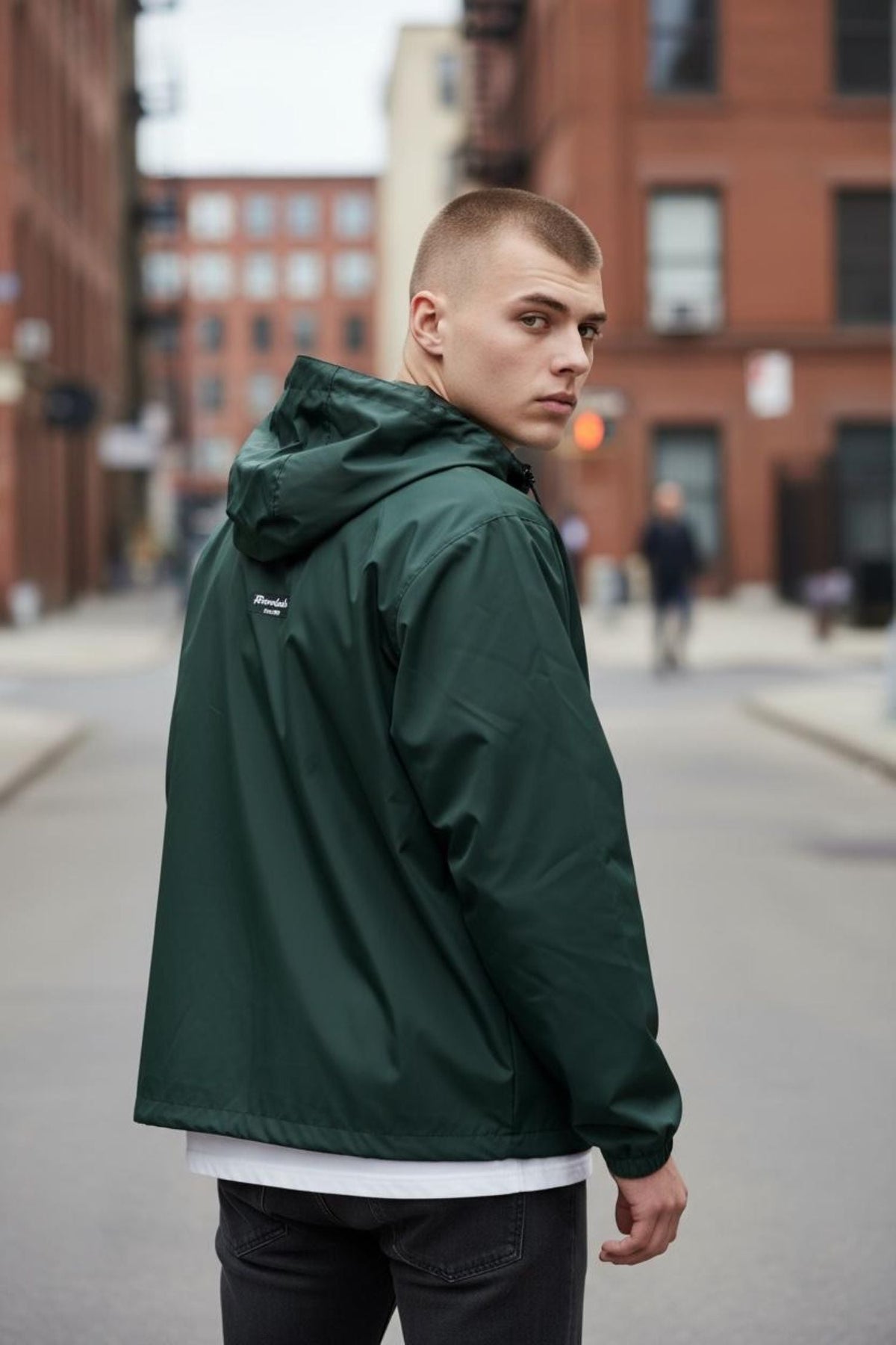 Streetwear model in a forest-green windbreaker on a city street