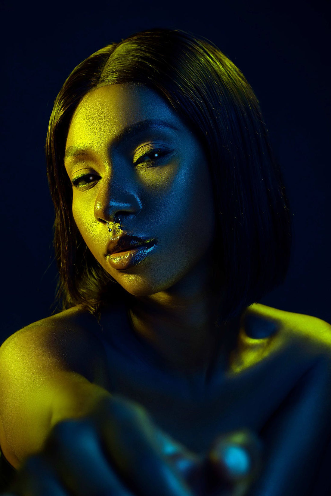 Fashion model in dramatic lighting wearing visible face and ear jewelry