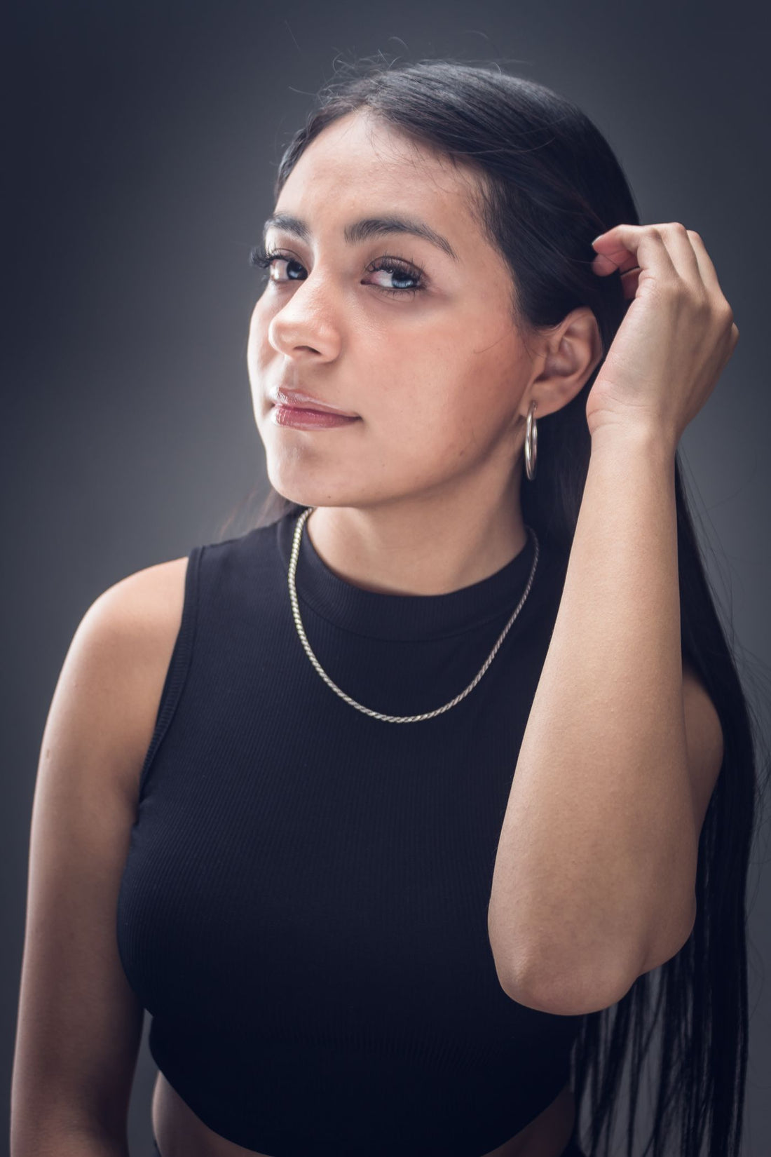 Woman in a black tank top wearing silver hoop earrings and a chain for weekend streetwear styling