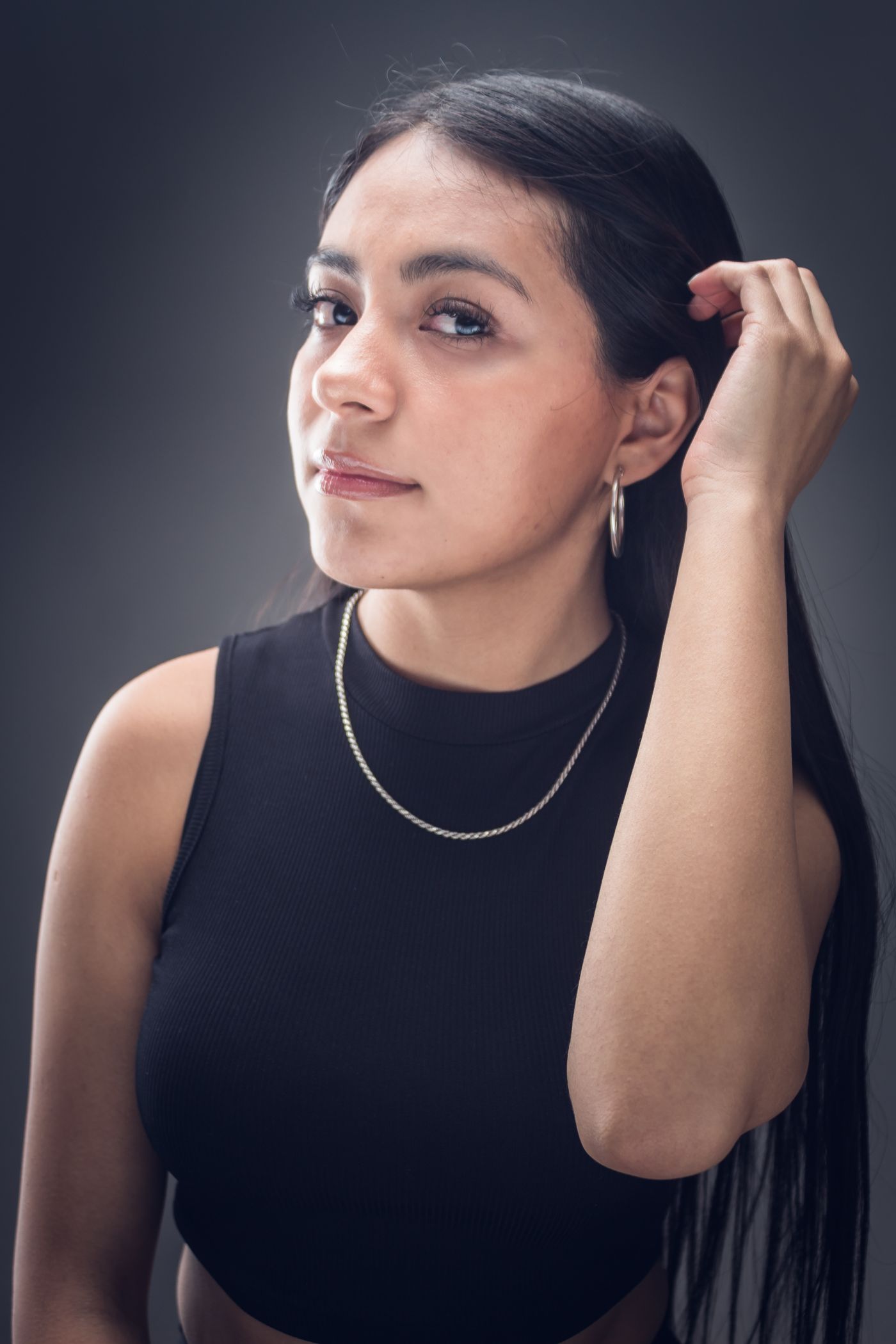 Woman in a black tank top wearing silver hoop earrings and a chain for weekend streetwear styling