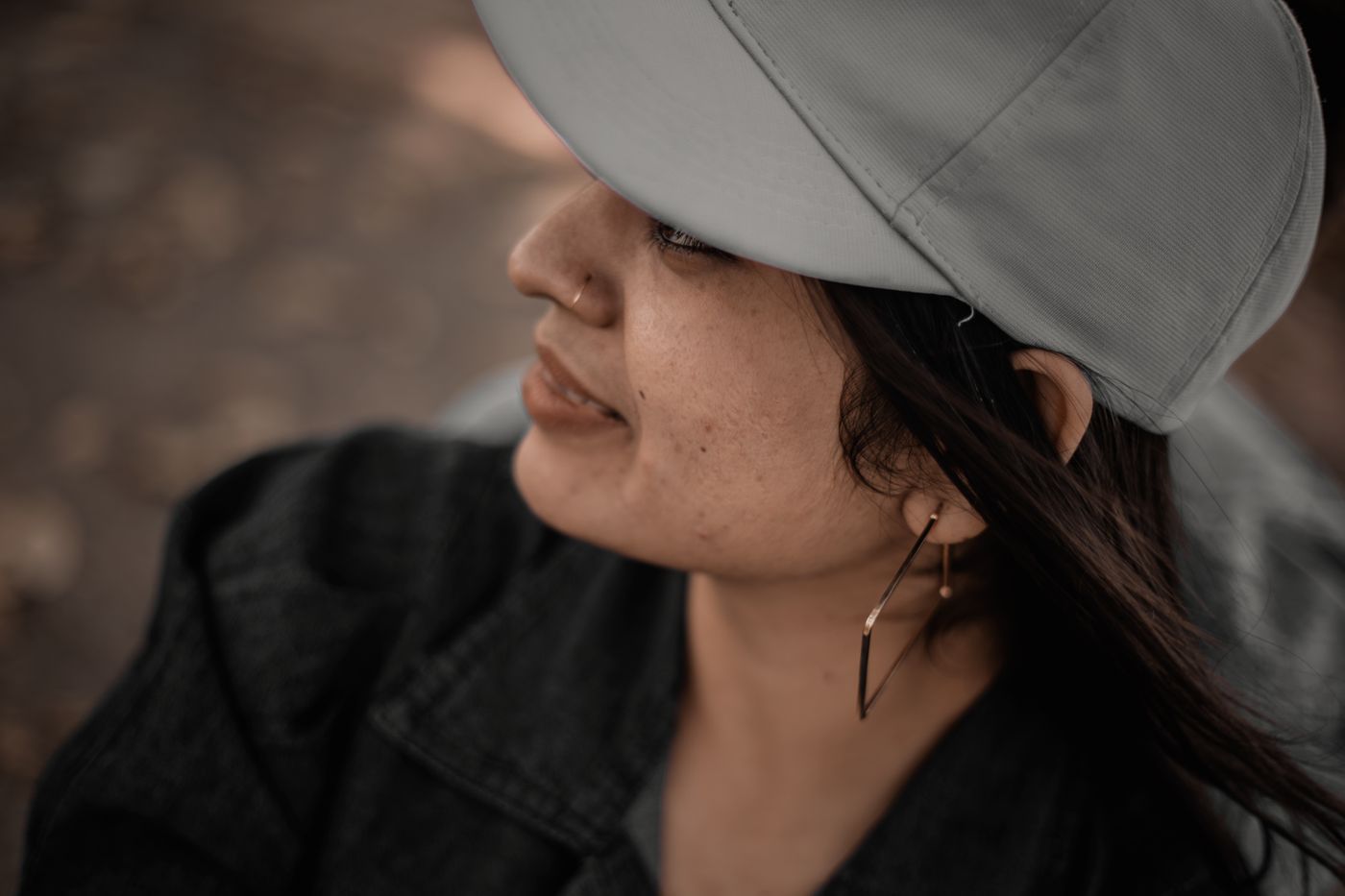Woman in gray cap and dark jacket wearing soft dangling earrings