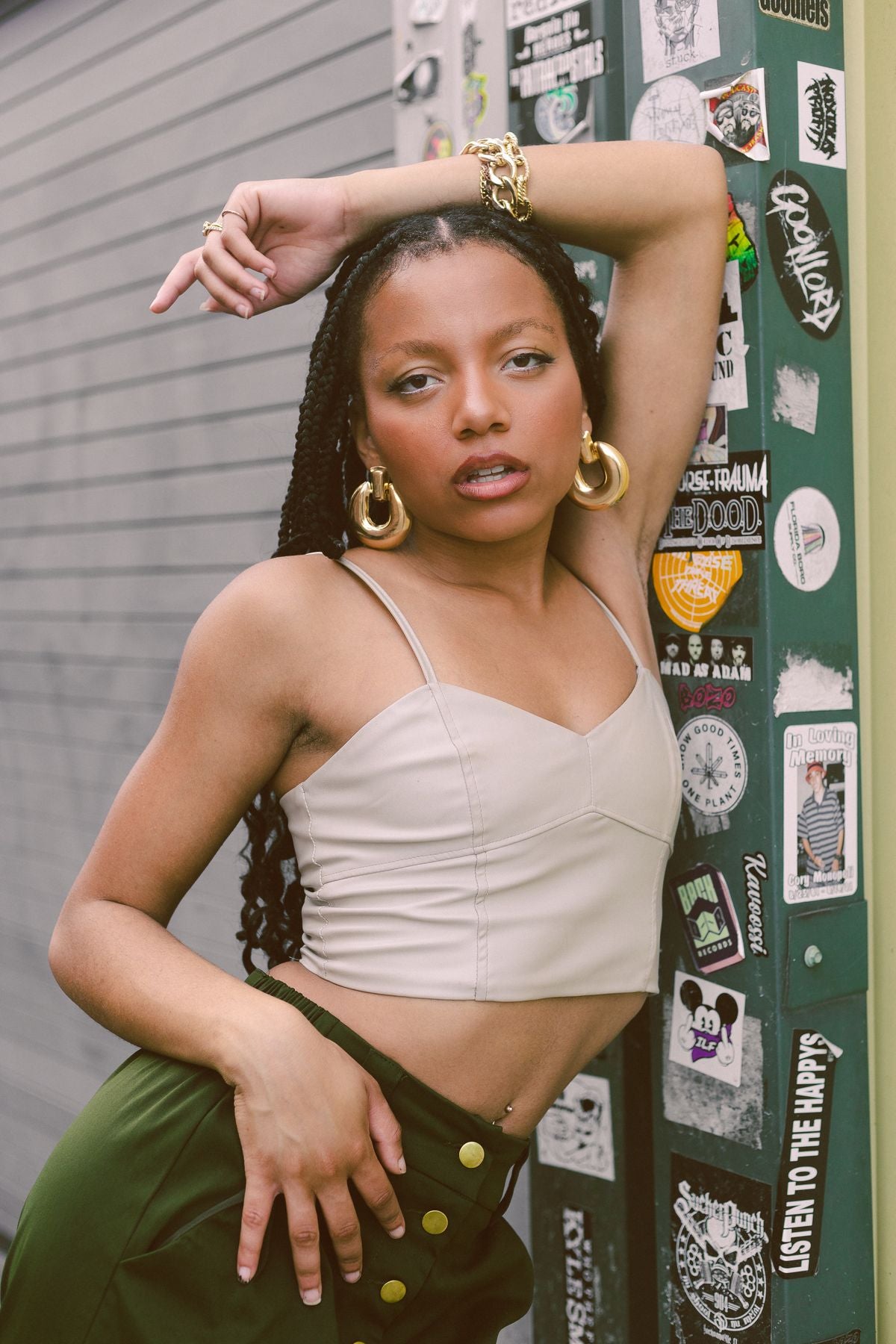 Woman wearing oversized gold hoop earrings with sage trousers in a street-style portrait