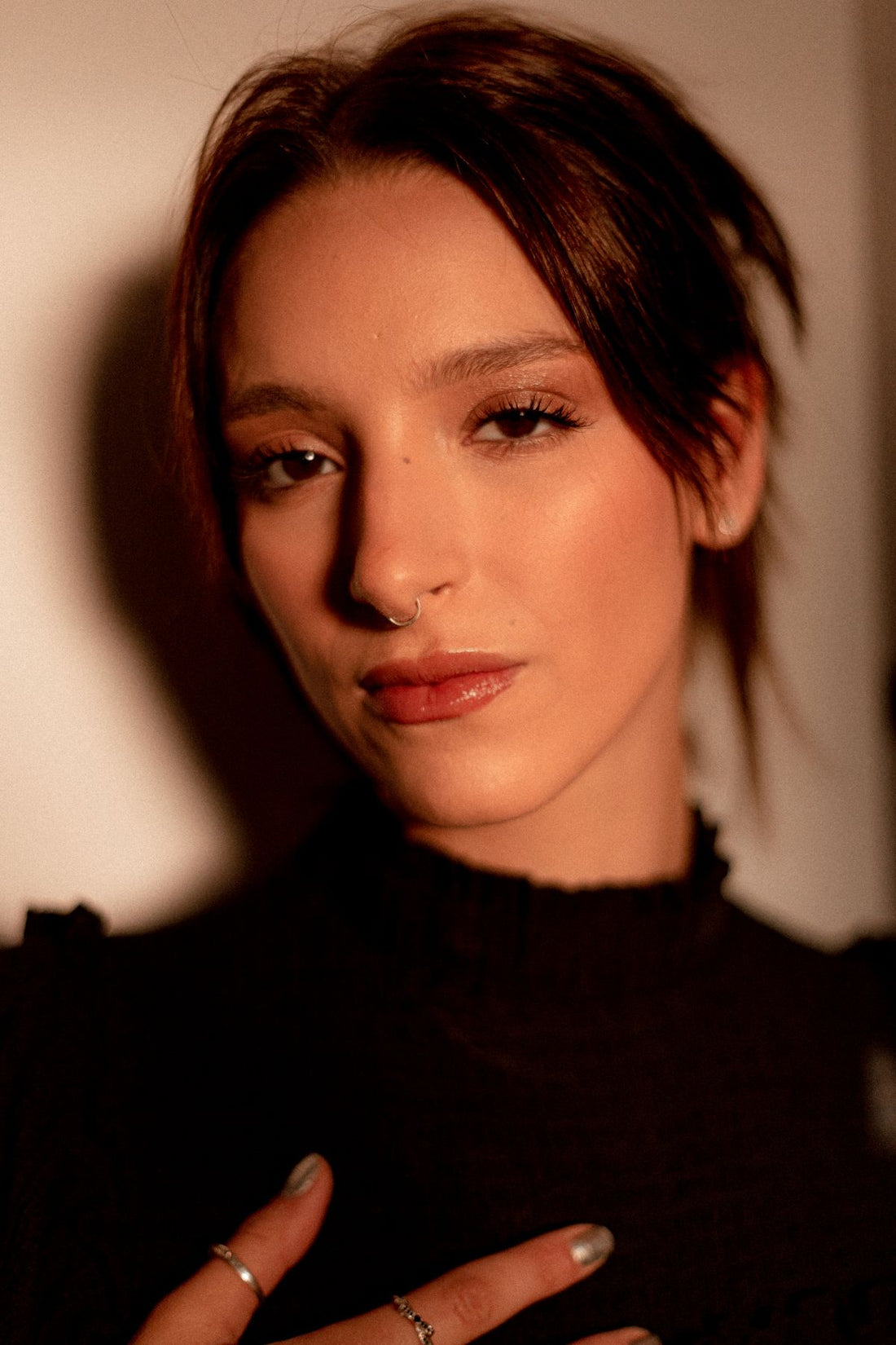 Close-up portrait of a woman with nose jewelry and warm evening makeup