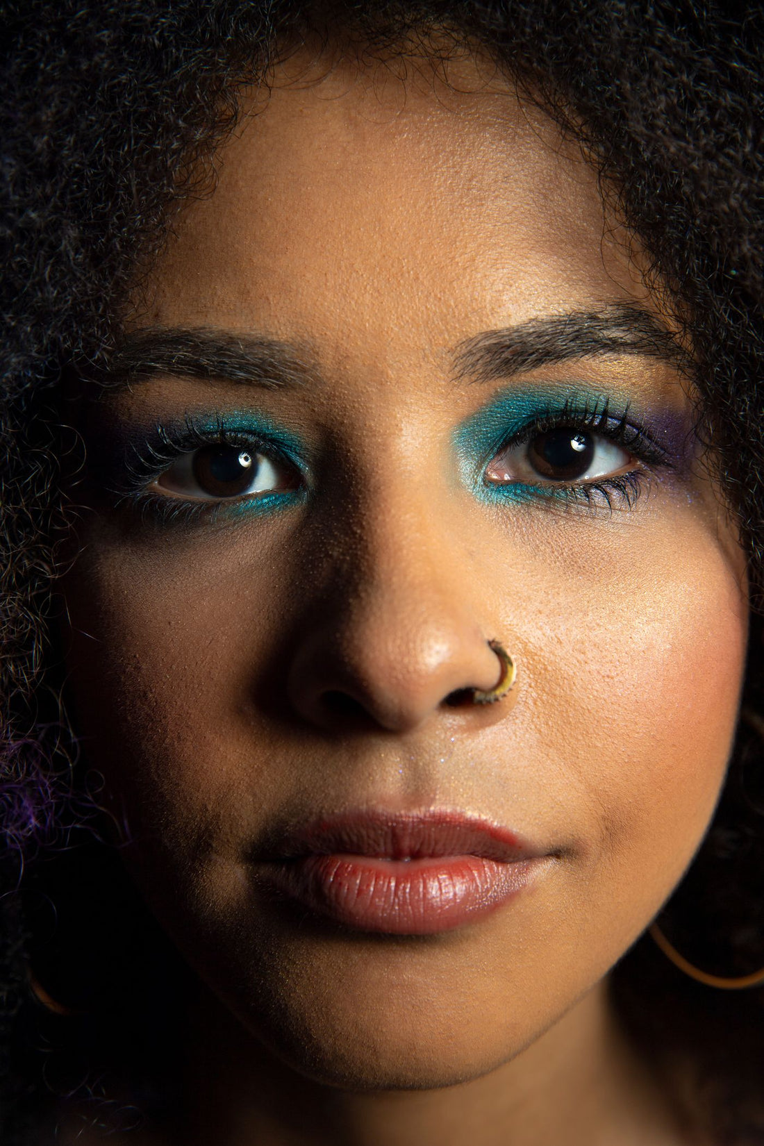 Close-up portrait with color-pop eye makeup and nose jewelry for festival styling