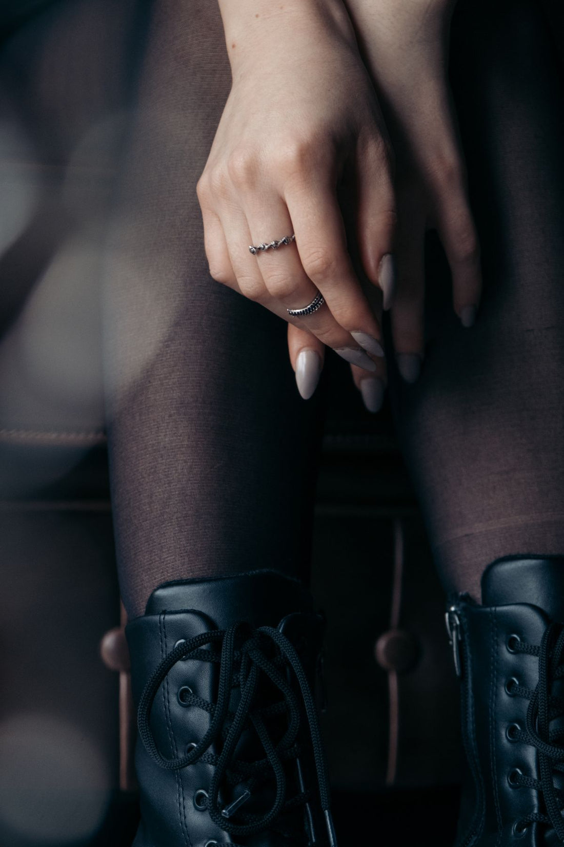 Fashion detail of a model styling rings with a polished black outfit