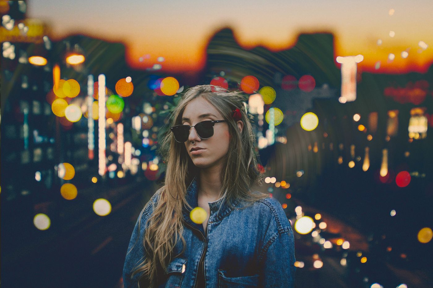 City portrait of a model in a denim jacket with face-framing jewelry at sunset