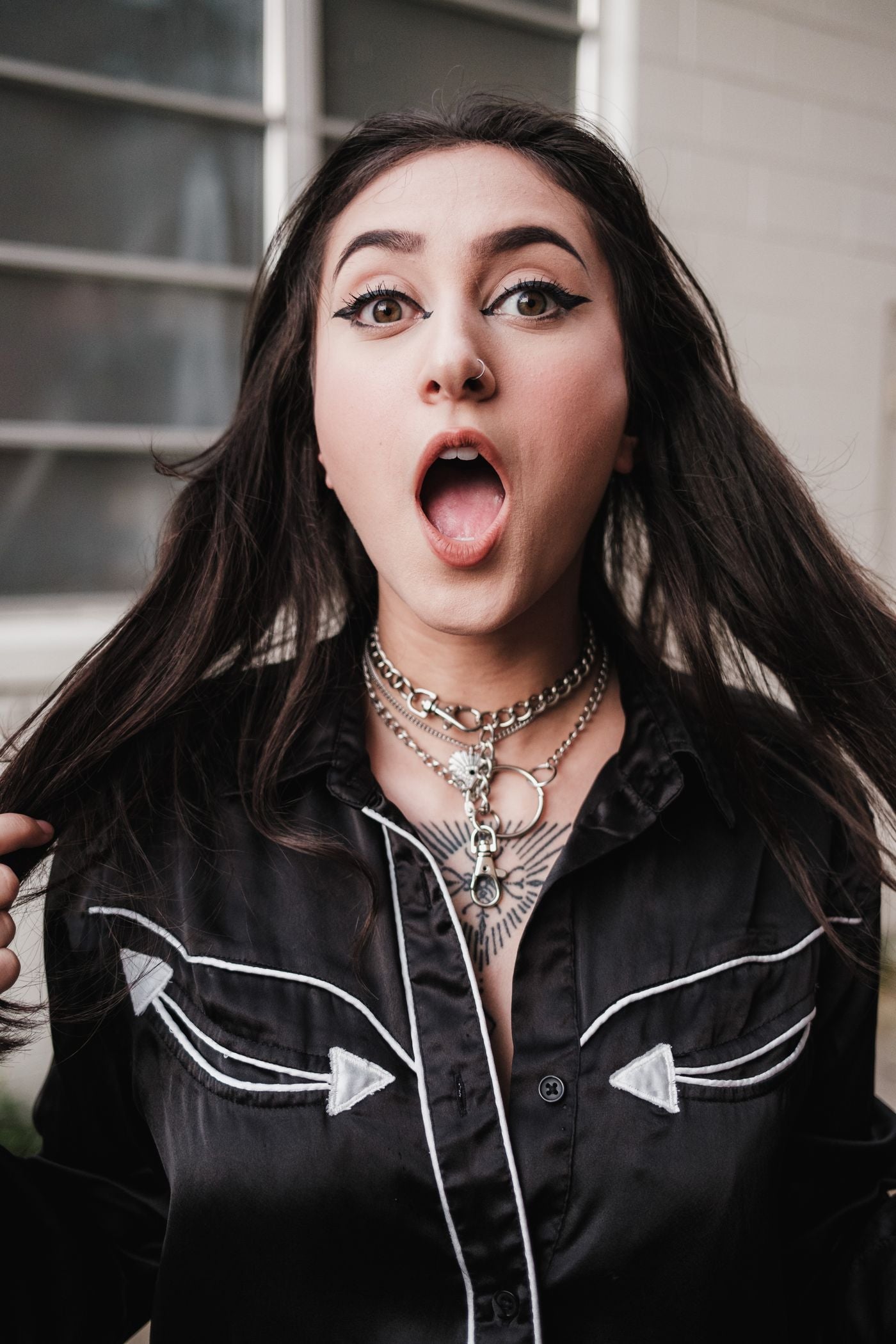 Young woman in a black shirt with bold eyeliner posing outdoors