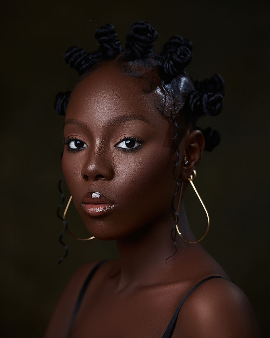 Portrait of a woman wearing large gold hoop earrings with a black top