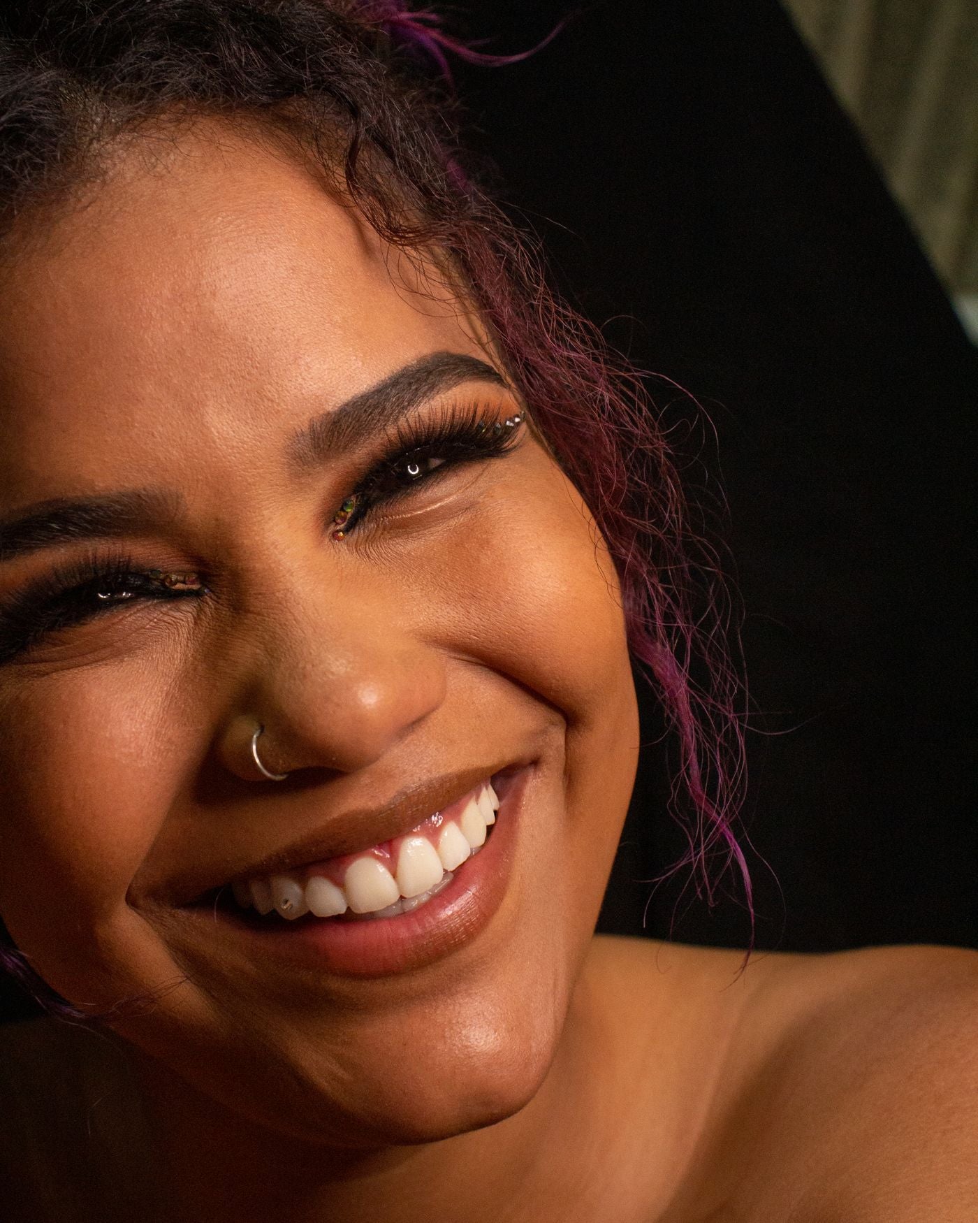 Smiling close-up portrait with nose jewelry and warm beauty styling