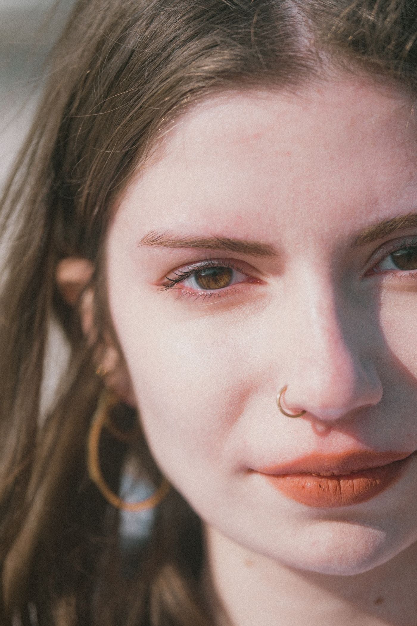Minimal close-up portrait of a woman with nose jewelry and soft morning light
