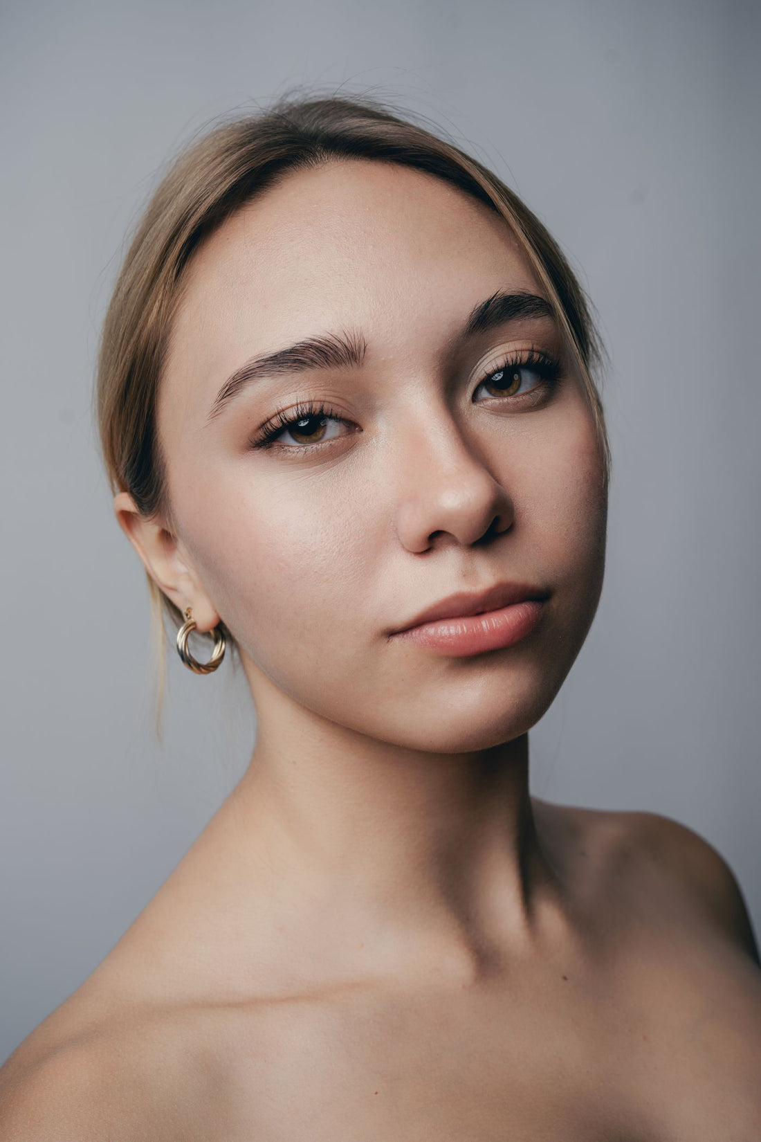 Close-up portrait of a woman wearing soft hoop earrings for a clean city jewelry look