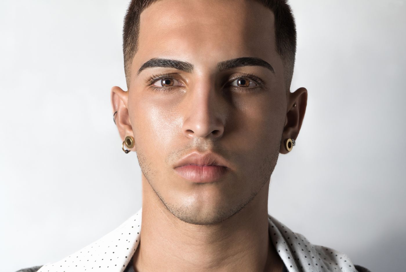 Clean portrait of a model in white layers wearing small ear jewelry
