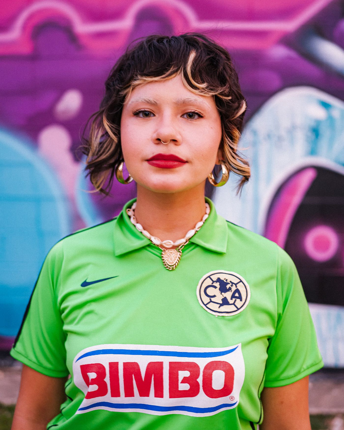Streetwear model in a bright soccer jersey posing in front of a graffiti wall