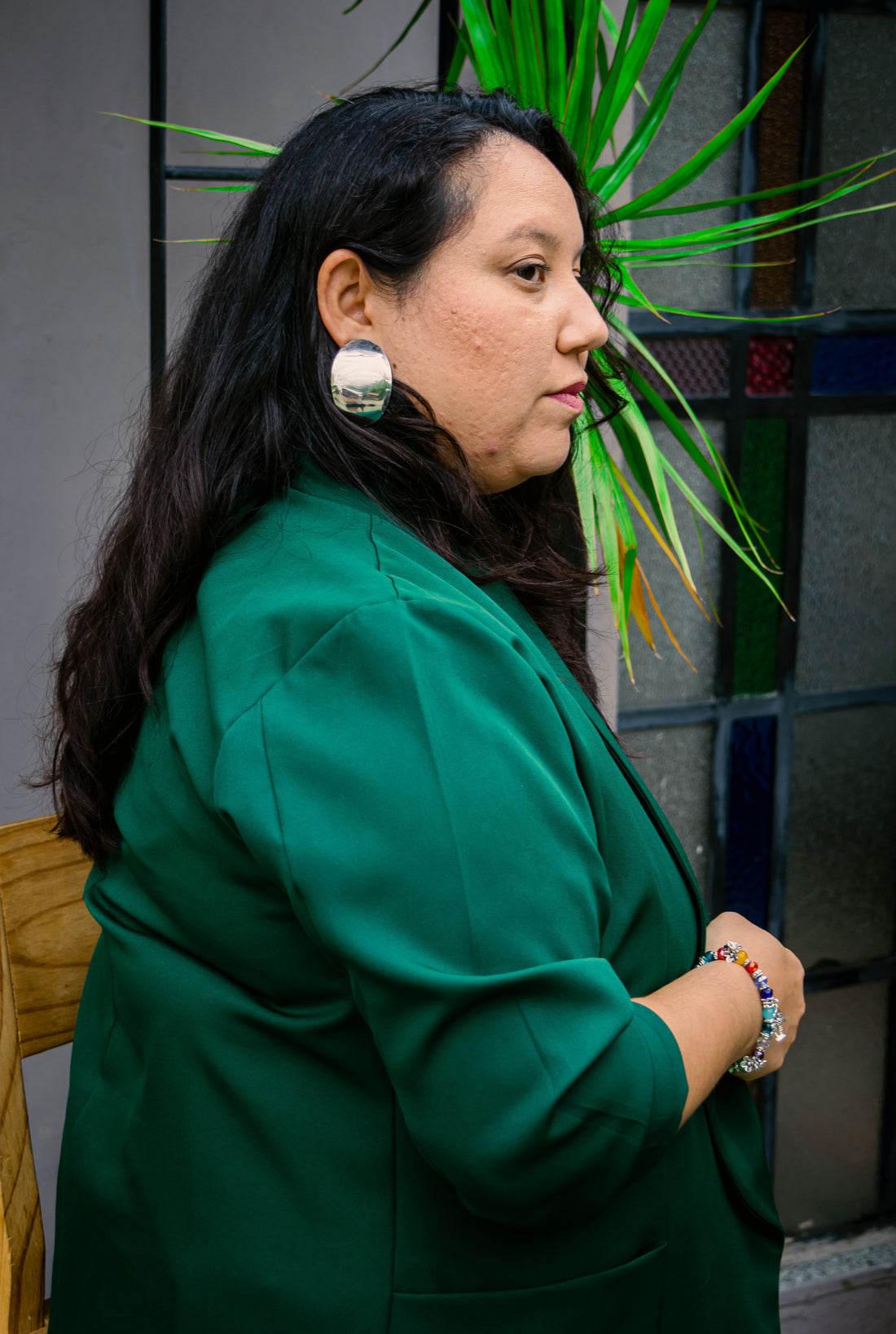 Centered side-profile portrait in a green blazer with a silver ear detail