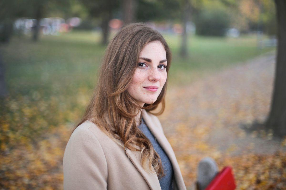 Woman in a camel coat outdoors for a soft city-walk jewelry styling guide