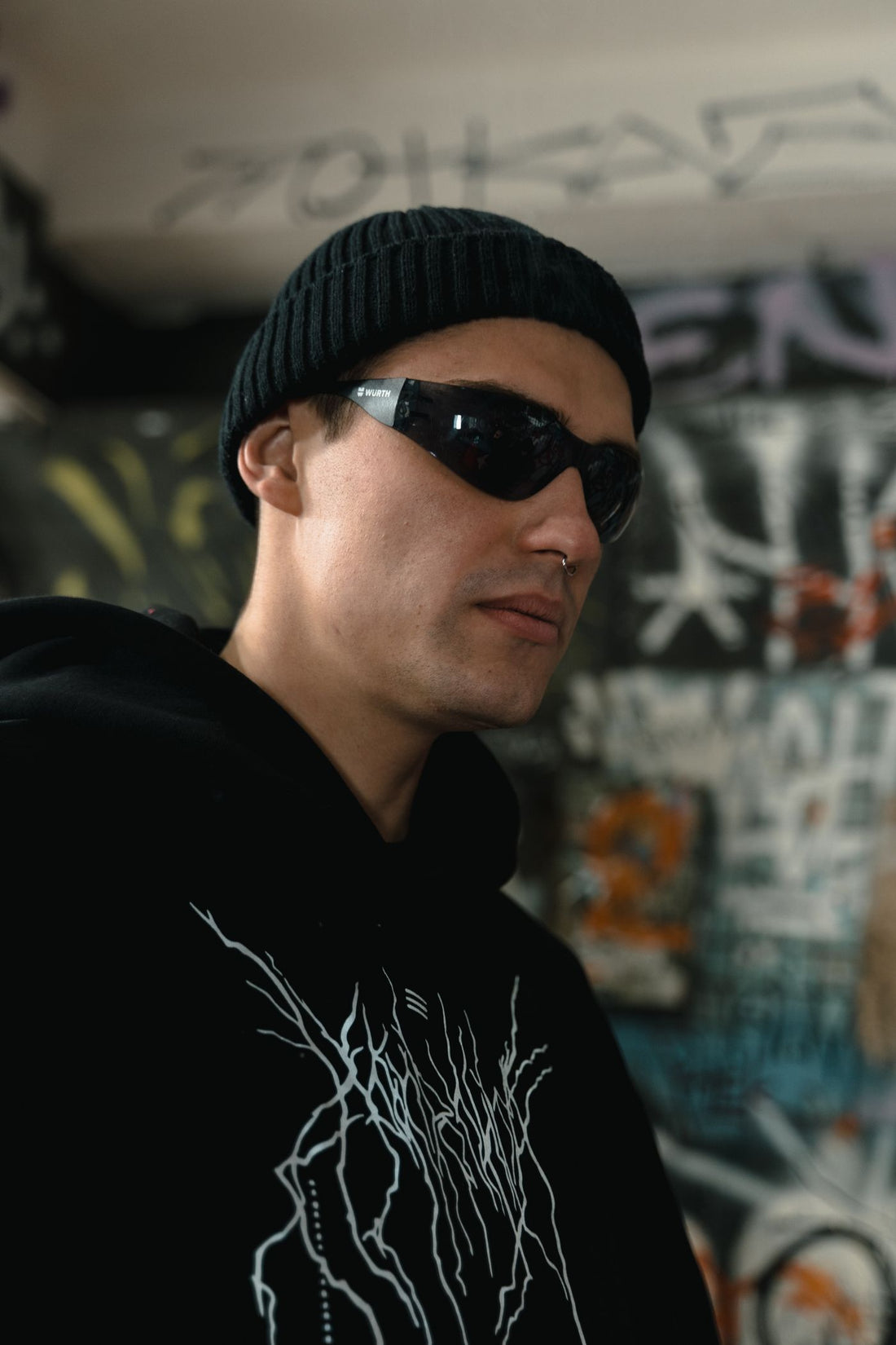 Streetwear portrait of a model in a black beanie and hoodie with face-framing jewelry