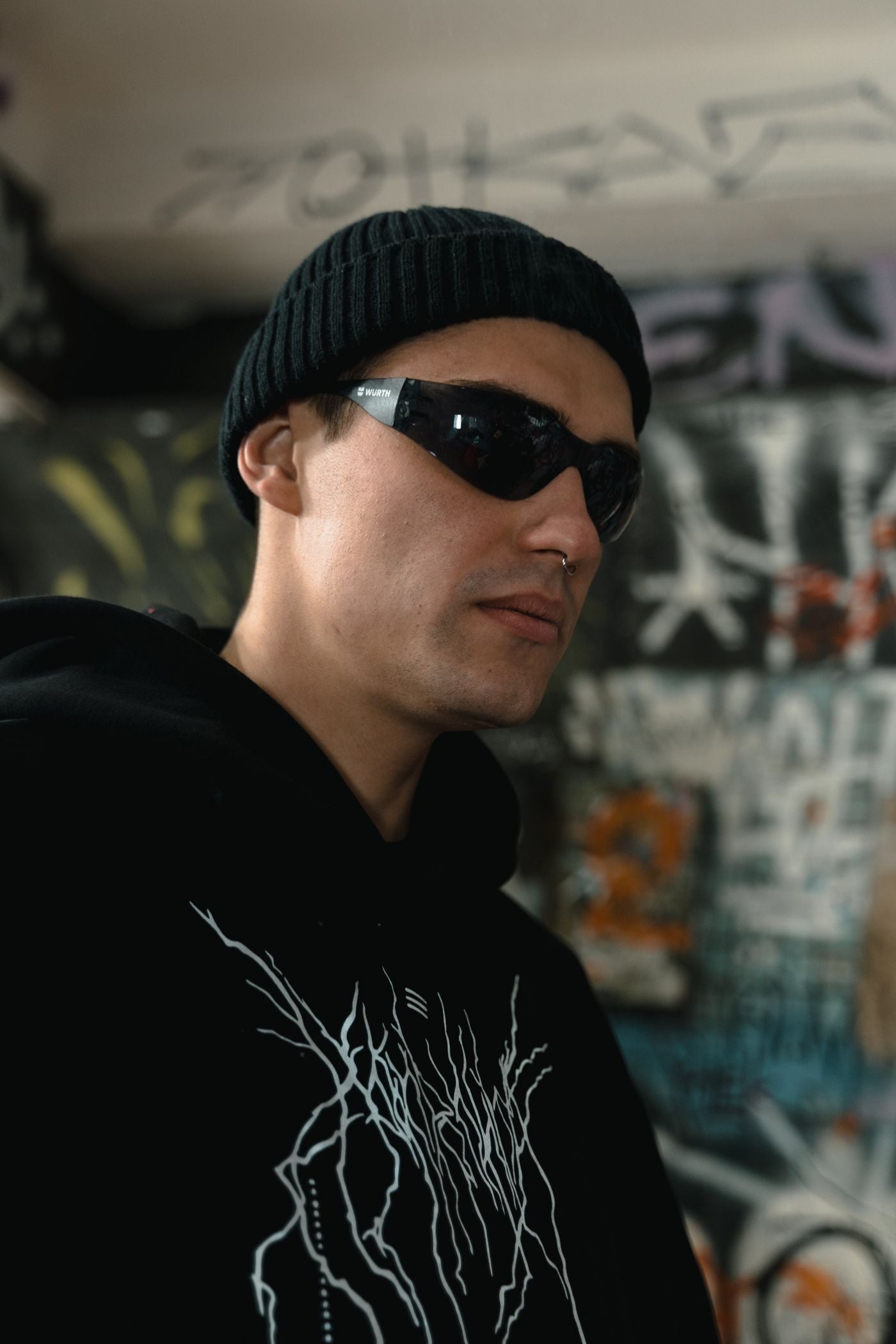 Streetwear portrait of a model in a black beanie and hoodie with face-framing jewelry