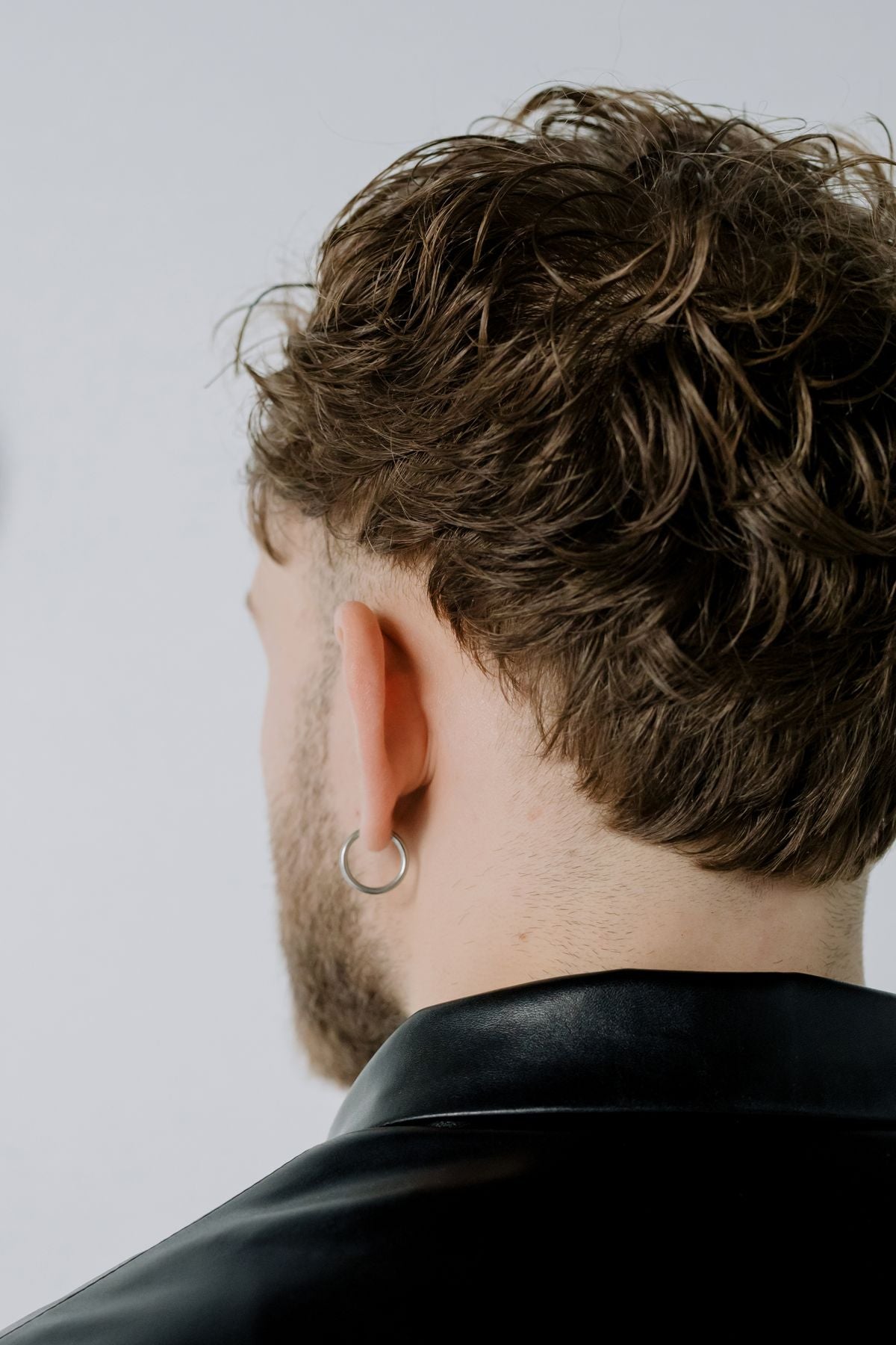 Close-up streetwear portrait of a model with hoop earrings and a bold layered look