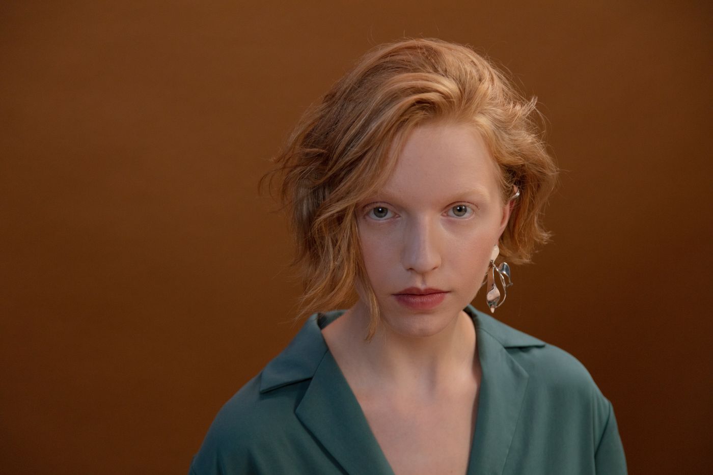 Minimal portrait of a woman with short hair wearing a clean blazer and ear jewelry