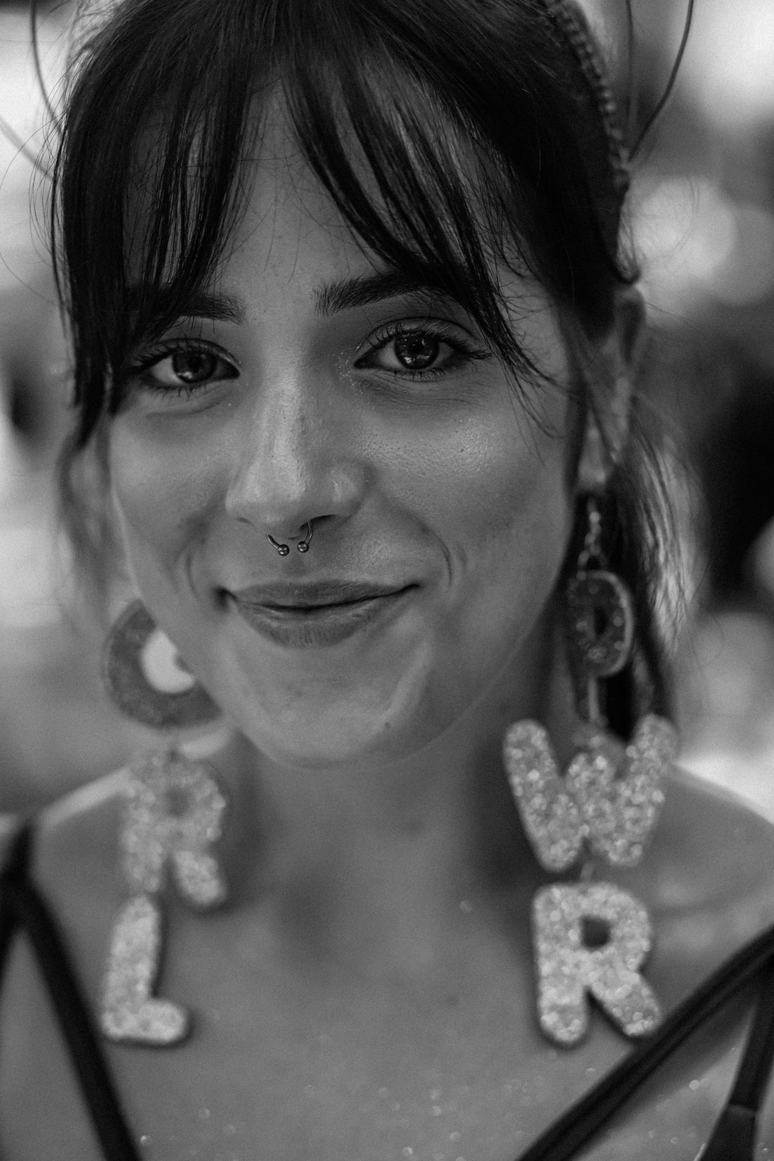 Smiling woman in a monochrome portrait wearing a nose ring and bold earrings