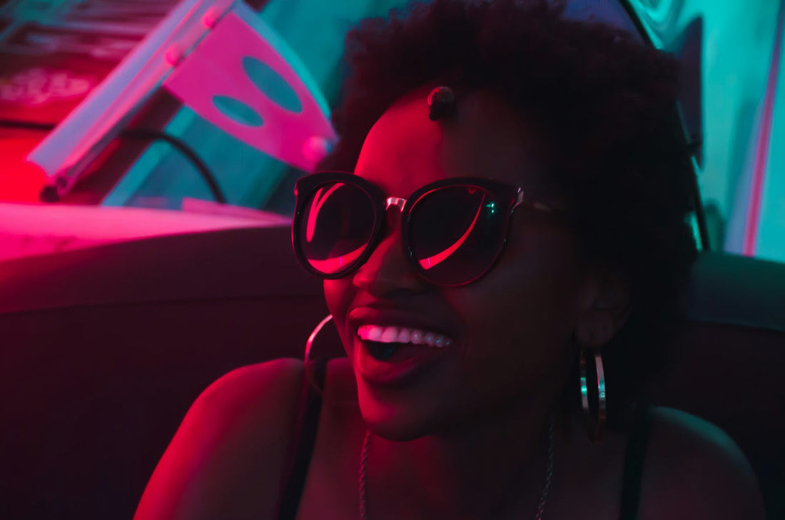 Night-out outfit inspiration with black sunglasses and hoop earrings in pink and blue light