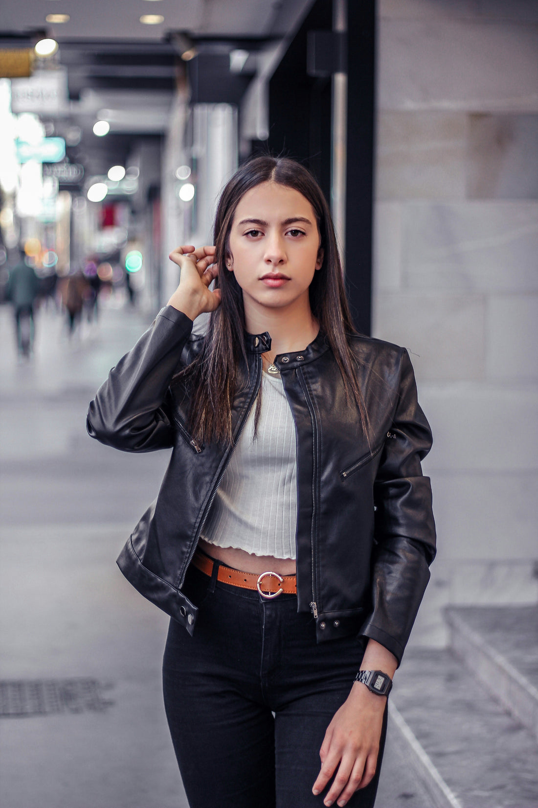 Woman in a black leather jacket smiling outdoors with a centered portrait composition